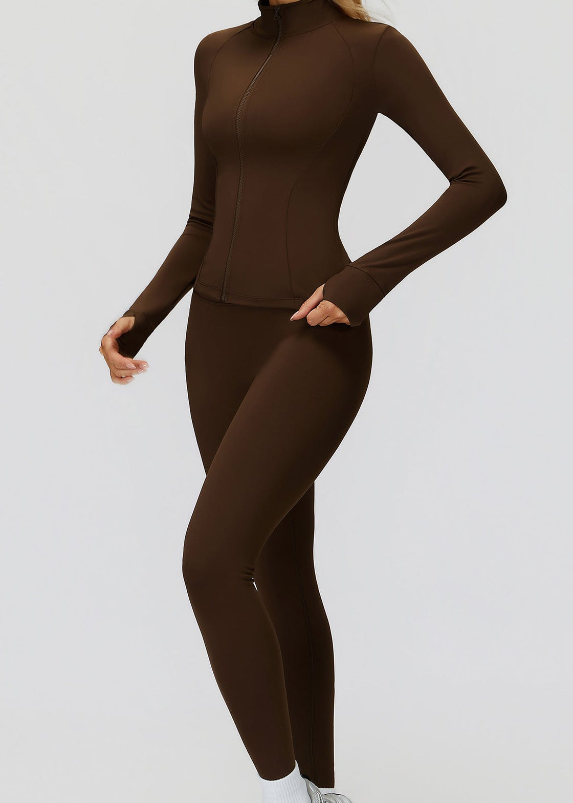 Brown full-zip golf jacket zipped to the collar, full-length side view worn with matching leggings and sneakers