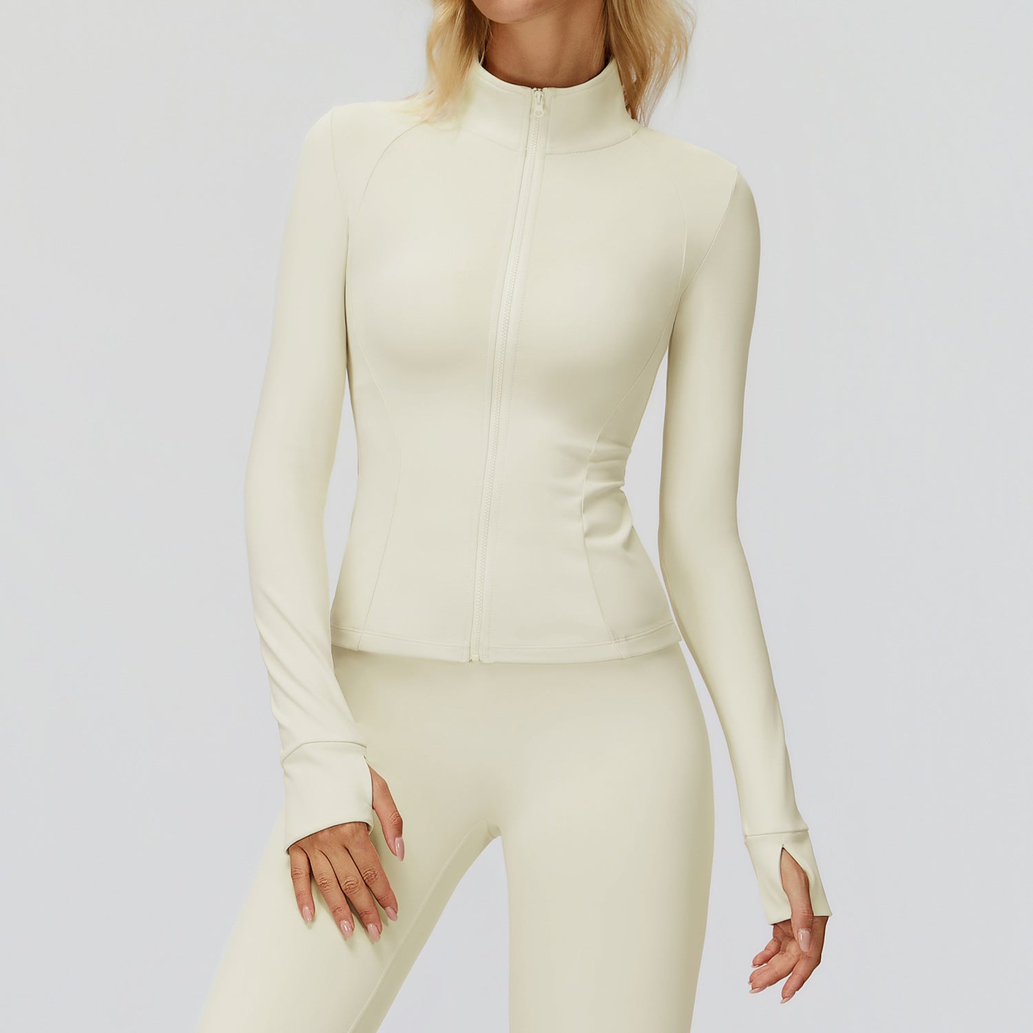 Cream stand collar golf jacket zipped to the neck, front view worn with matching cream leggings