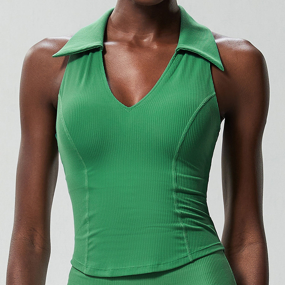 Green ribbed sleeveless golf top on a model, front view showing the ribbed knit and contour seams