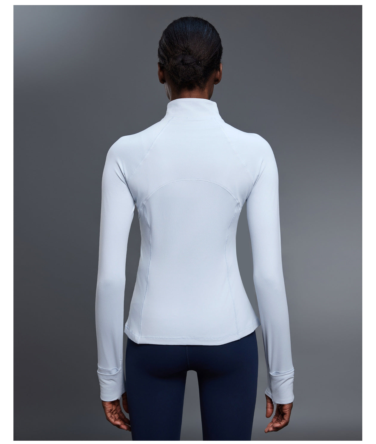 Back view of light blue quarter-zip pullover showing the stand collar, curved seams and thumbhole cuffs