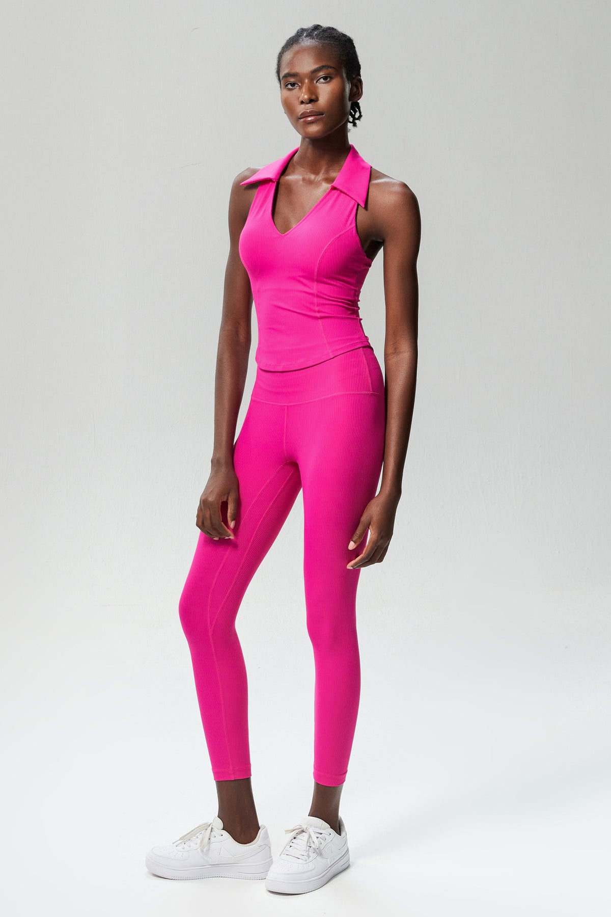 Model standing in the fuchsia ribbed sleeveless golf top with matching leggings, full-length front view