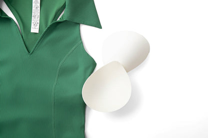 Green ribbed sleeveless golf top laid flat, showing the removable cups and the inside care label