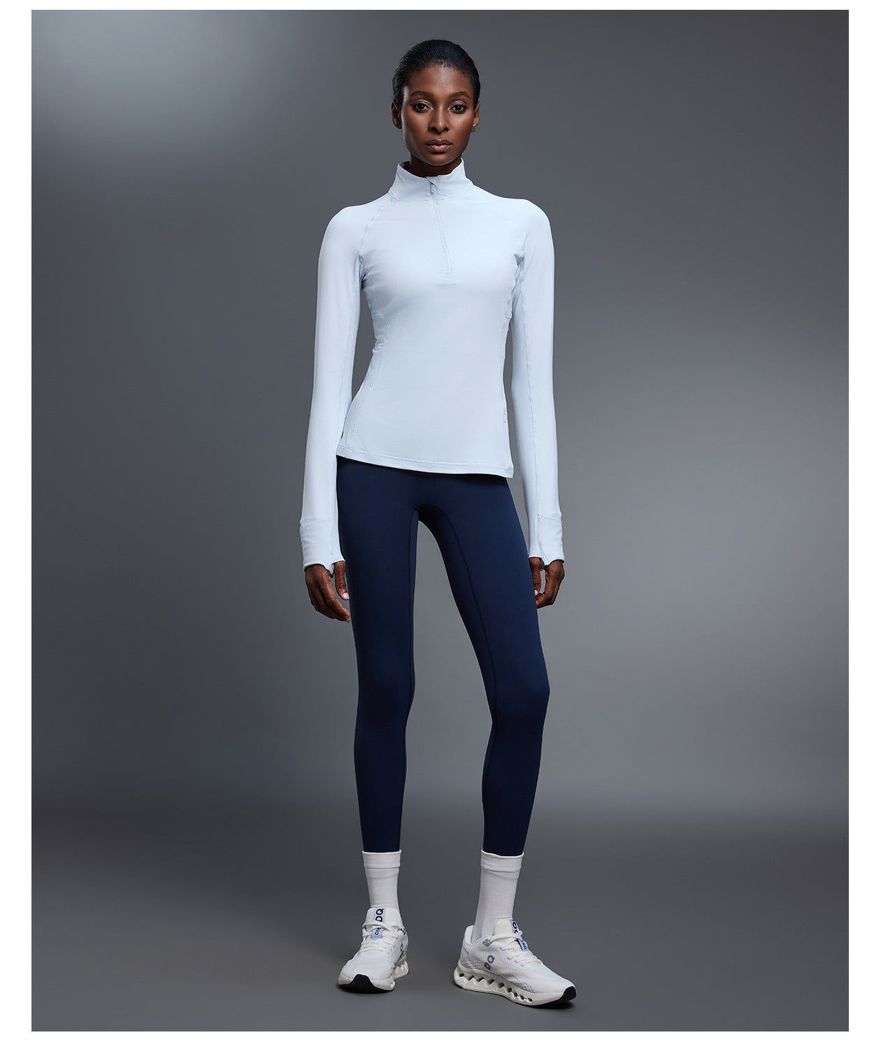 Light blue quarter-zip golf pullover with navy leggings, full-length front view showing thumbhole cuffs