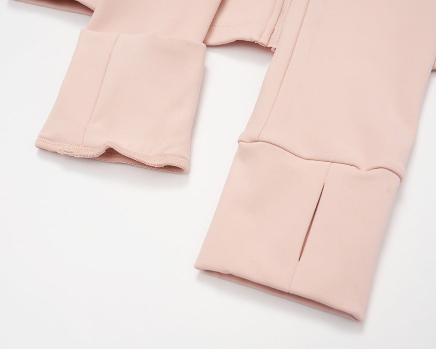 Close-up of the thumbhole slits in the cuffs of the pink full-zip golf jacket, laid flat