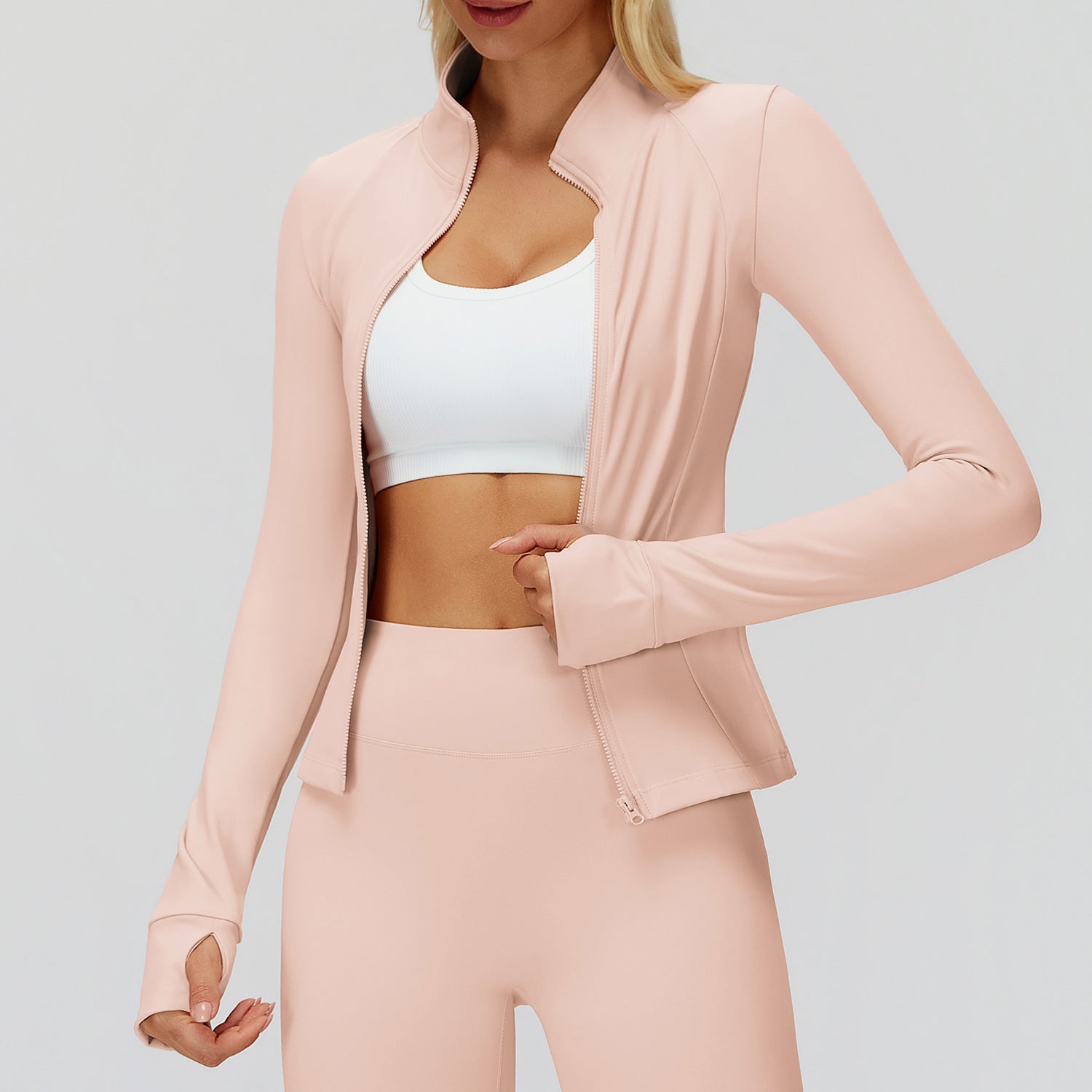 Pink full-zip golf jacket worn open over a white sports bra, front view showing the stand collar